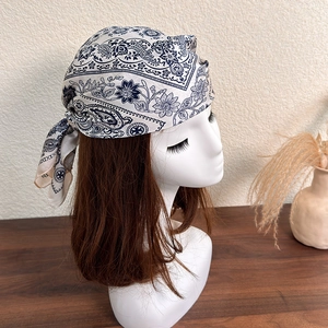 Detailed shot of navy blue paisley silk-like headscarf tied around a mannequin head