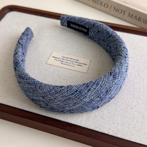 Close-up of blue tweed padded headband with a handmade label on wooden tray