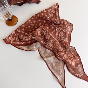 Flat lay of a brown paisley cotton scarf with retro aesthetic and artistic props