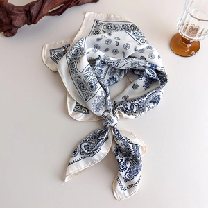 Close-up of silk square scarf featuring blue paisley prints and elegant draped knots