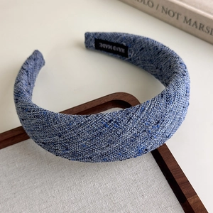 Detail of blue tweed headband featuring a soft padded texture and handmade inner label