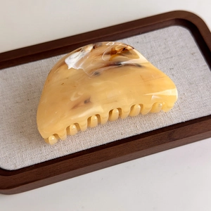 Close-up of marble pattern hair claw clip with amber and cream yellow resin texture