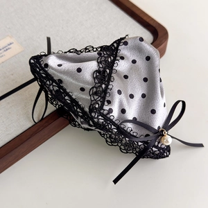 Close-up of satin polka dot fabric with delicate lace trim and pearl bow detail