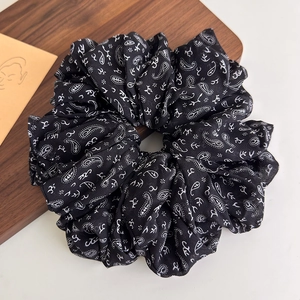 Close-up of black oversized scrunchie featuring vintage white paisley patterns on chiffon