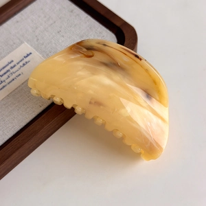 Close-up of amber textured hair claw clip with cream and brown marble finish