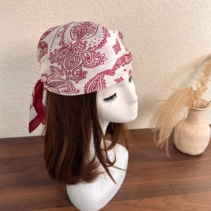 Detail of silk square scarf featuring red paisley patterns on a mannequin head