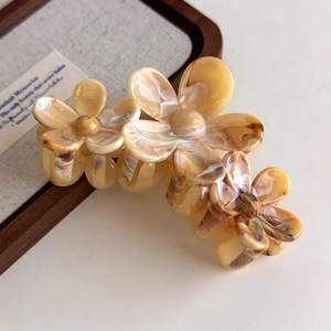 Detail view of marble textured flower hair claw clip with amber resin finish on a tray