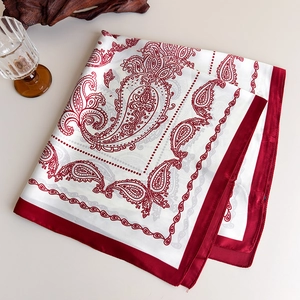 Detail of red paisley satin scarf featuring smooth silk-like texture and bold border