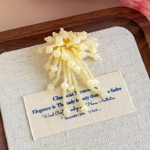 Dettaglio ravvicinato di un charm per scarpe a fiore con perline gialle su vassoio in legno