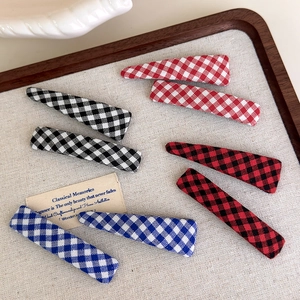 Classic plaid fabric hair clips set in red, blue, and black patterns on a wooden tray