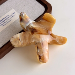 Close-up of starfish hair claw clip with yellow and brown marble amber texture