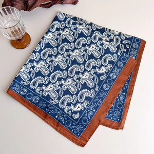 Detail of blue and white paisley silk scarf with contrast caramel brown borders