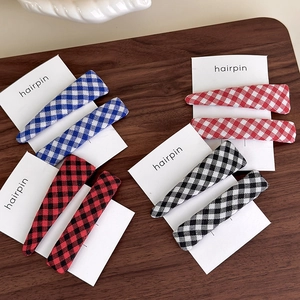 Set of four plaid fabric hair clips in blue, red, and black on a rustic wooden background