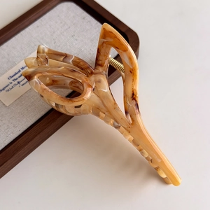 Macro detail of amber tulip claw clip with golden metal spring and tortoise texture