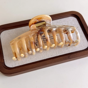 Macro view of a large marble texture hair claw clip on a rustic wooden tray