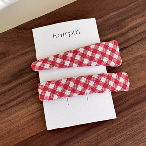 Detail of red gingham pattern fabric hair clips set on a rustic wooden surface