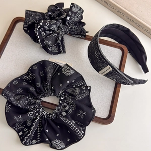 Detail view of vintage paisley hair accessory set with black bow clip and headband
