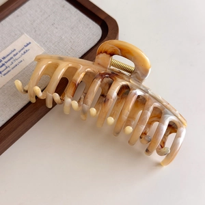 Macro detail of large amber tortoiseshell hair claw clip with golden metal spring