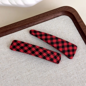 Close-up of red and black checkered fabric hair clips set on a rustic wooden tray