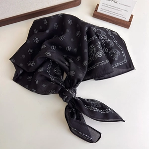 Detail of a black paisley silk scarf with a soft texture and delicate rolled edges