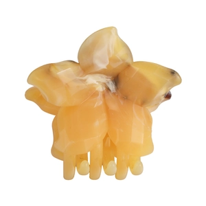 Detail of flower shaped claw clip with amber marble texture and acetate finish