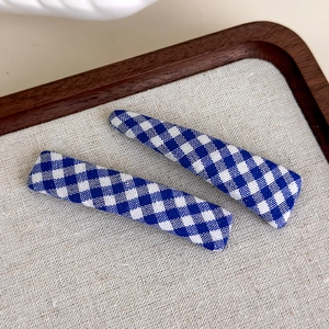 Close-up of blue and white gingham fabric hair clips set on a rustic display
