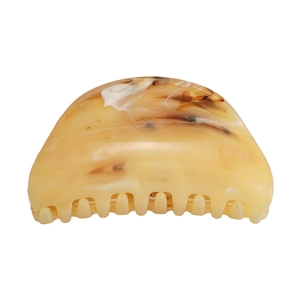 Macro detail of marble pattern hair claw clip with amber and cream acetate textures