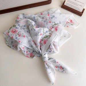 Detail of floral print cotton scarf with delicate pink and blue patterns on white fabric