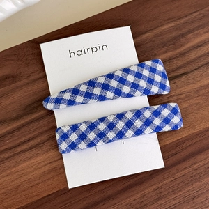 Detail of blue and white checkered fabric hair clips set on a wooden surface