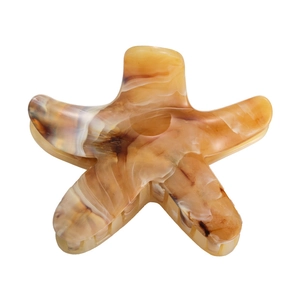 Detailed close-up of a starfish-shaped amber tortoiseshell acetate hair claw clip for women
