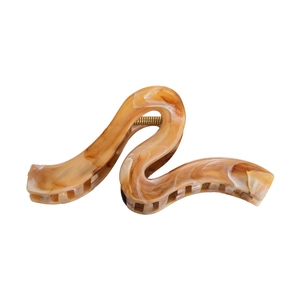 Detail of S-shaped amber tortoiseshell hair claw clip with cream marble texture
