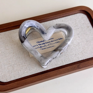 Detail of heart-shaped marble acetate hair claw clip with golden metal spring