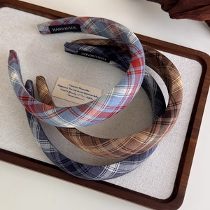 Three retro plaid fabric headbands in red, blue and brown on a wooden tray display