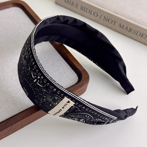Detailed side view of vintage paisley headband with handmade label on wooden tray