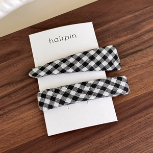 Close-up of black and white gingham fabric-wrapped hair clips on a wooden display