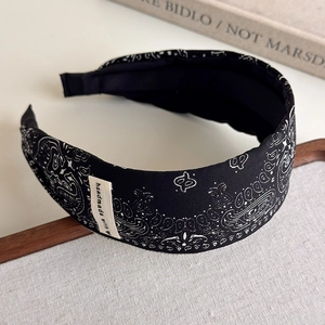 Detail of a vintage black paisley fabric headband with handmade label on textile background