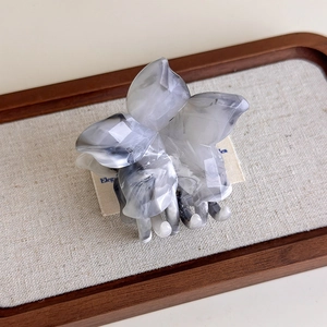 Detail of flower-shaped large hair claw clip with grey ink marble pattern and acetate texture