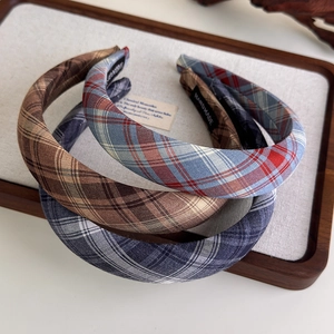 Detailed close-up of three handmade plaid fabric headbands displayed on a wooden tray