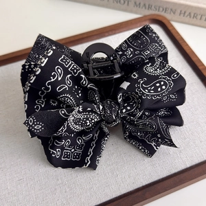 Detailed macro view of black paisley print bow hair claw clip with strong spring mechanism