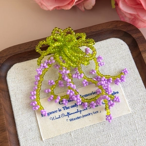 Dettaglio di ciondoli a fiore in perline fatti a mano verde e viola per zoccoli