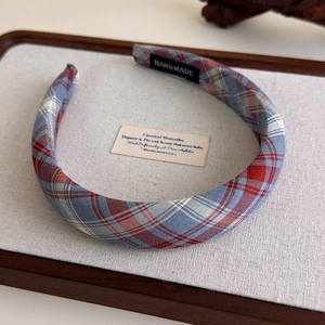 Detail of red and blue plaid fabric headband with handmade label on rustic wooden display