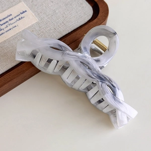 Macro detail of ink-wash marble hair claw clip with golden metal spring and knot design