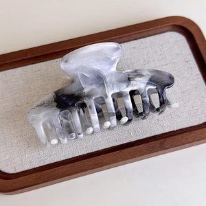Detail of large ink-wash marble pattern hair claw clip with acetate texture and metal spring