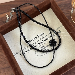 Detail shot of a double-layered black rose beaded choker necklace in a vintage display box