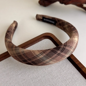 Detailed close-up of brown Scottish plaid headband with woven handmade label inside
