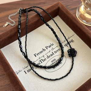 Close-up of double-layer black beaded necklace with rose pendant in a vintage box
