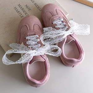 Détail de baskets en daim rose avec des lacets élégants en dentelle blanche à gros nœuds
