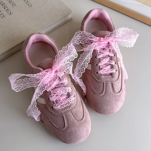 Détail d'une basket en daim rose avec de larges lacets en dentelle et des accents de perles