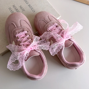 Gros plan de baskets en daim rose avec des nœuds en dentelle élégants et style balletcore