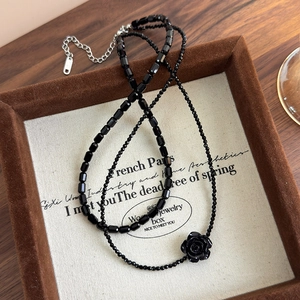 Detailed macro view of black rose pendant and beaded double-layer choker necklace